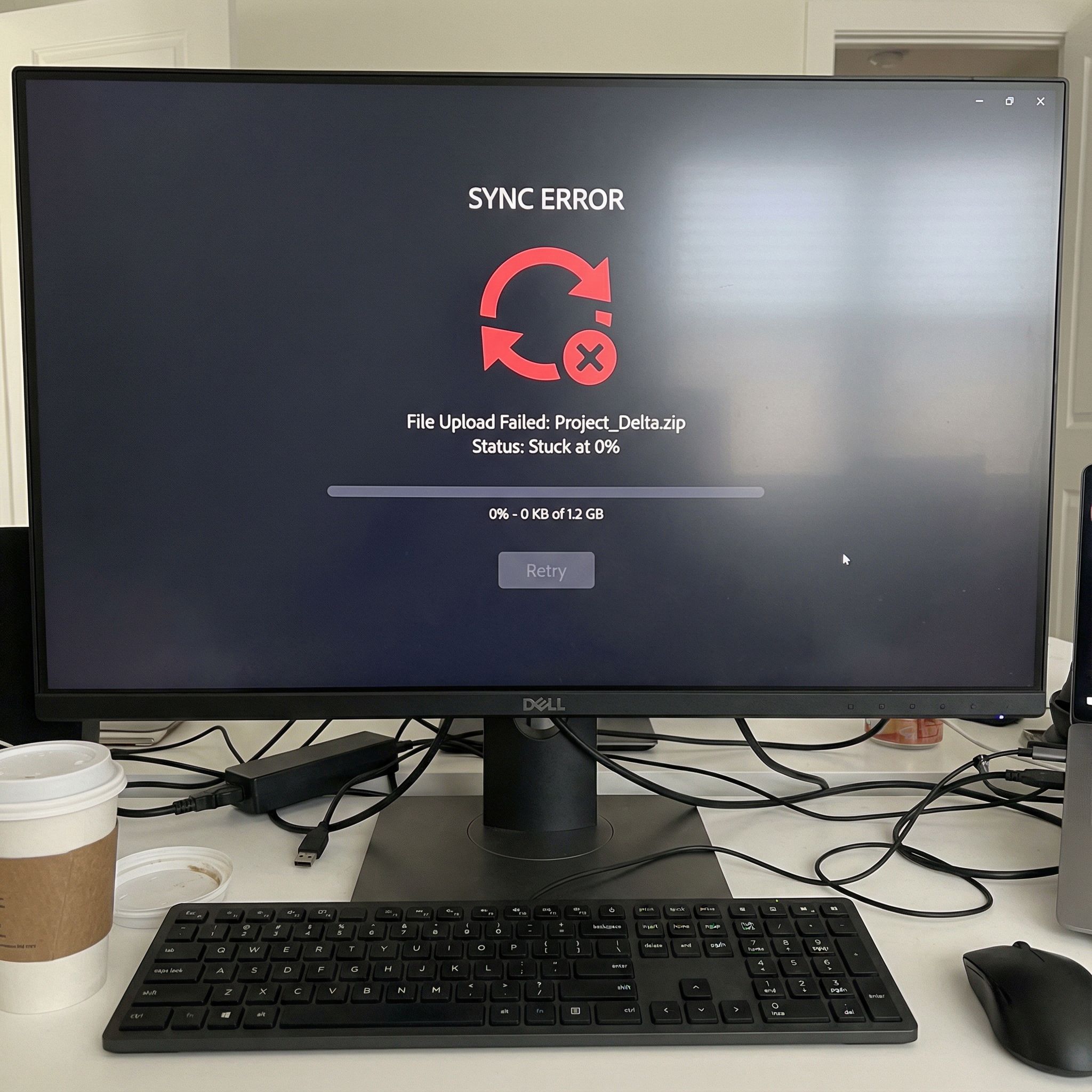 검은색 컴퓨터 화면에 빨간색 동기화 오류 아이콘이 표시되고, 진행률 막대는 멈춘 채 파일 업로드는 0%에서 정지한 모습이다.